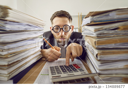 Business man working at the desk in office with a pile of folders and a stack of papers. Business man working at the desk in office with a pile of folders and a stack of papers. 134889877