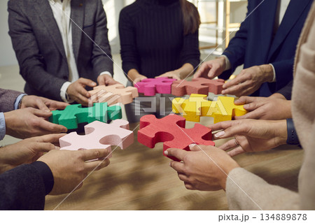 Hands of a group of business people assembling jigsaw puzzle. Cooperation, teamwork support concept Hands of a group of business people assembling jigsaw puzzle. Cooperation, teamwork support concept 134889878