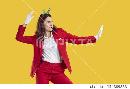 Cool woman in red suit and New Year's accessories is dancing and having fun at New Year's party. Cool woman in red suit and New Year's accessories is dancing and having fun at New Year's party. 134889888