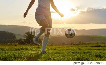 広い屋外フィールドを背景に、サッカーボールを蹴る足元のみを捉えたスポーツシーン。 顔や個人が特定でき 134889898