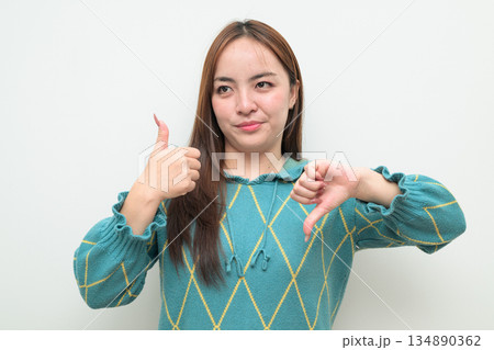 Portrait of a young Asian woman against white background confused Portrait of a young Asian woman against white background confused 134890362