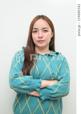 Portrait of a young Asian woman against white background with arms crossed 134890382