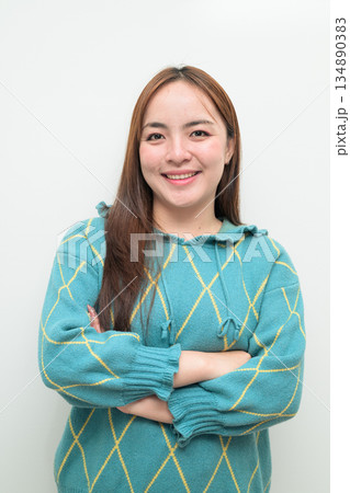 Portrait of a young Asian woman against white background with arms crossed 134890383