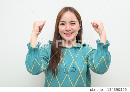 Portrait of a young Asian woman against white background with arm raised 134890396