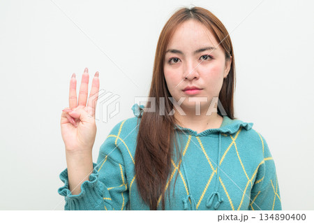 Portrait of a young Asian woman against white background showing number three with fingers 134890400
