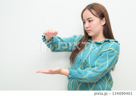 Portrait of a young Asian woman against white background measuring amount with hands 134890401
