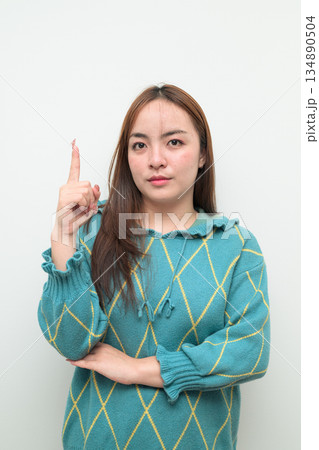 Portrait of a young Asian woman pointing finger against white background Portrait of a young Asian woman pointing finger against white background 134890504