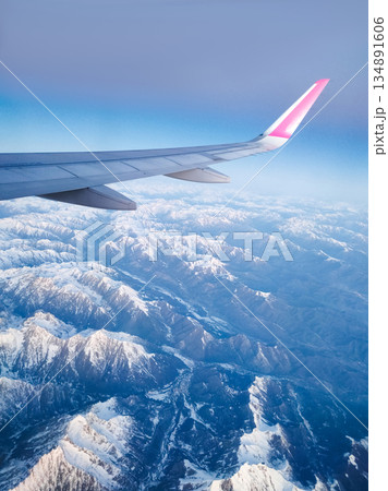 Aerial view of airplane wing flying over snow covered alps mountain range Aerial view of airplane wing flying over snow covered alps mountain range 134891606