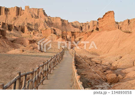 Footpath bridge at Kizil Red Stone Forest Scenic Area in Xinjiang , China is the strangely shaped red rock forests were carved by wind and sand over millions of years. 134893058