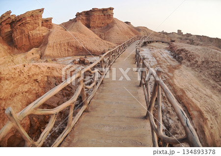 Footpath bridge at Kizil Red Stone Forest Scenic Area in Xinjiang , China is the strangely shaped red rock forests were carved by wind and sand over millions of years. The rocks are red in color. Footpath bridge at Kizil Red Stone Forest Scenic Area in Xinjiang , China is the strangely shaped red rock forests were carved by wind and sand over millions of years. The rocks are red in color. 134893378