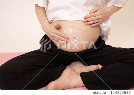 妊娠8ヶ月のお腹にクリームを塗る女性 妊娠8ヶ月のお腹にクリームを塗る女性 134893687