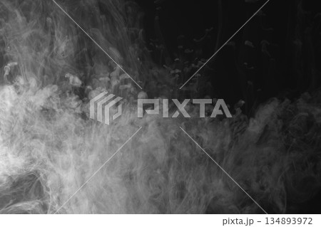 Abstract white smoke and fog drifting on dark black background with ample copy space, atmospheric texture for overlays and design 134893972