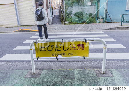 とびだし注意の標識と横断歩道　住宅街を歩く人の後ろ姿 134894069