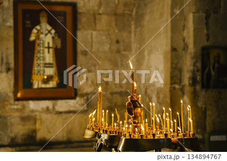 Candles in a Christian Orthodox church background. Flame of candles in the dark sacred interior of the temple 134894767