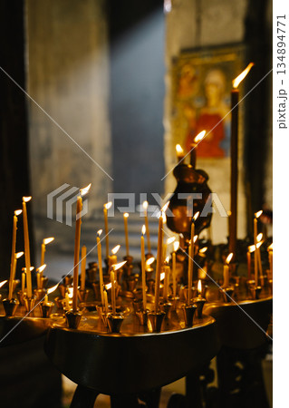 Candles in a Christian Orthodox church background. Flame of candles in the dark sacred interior of the temple 134894771