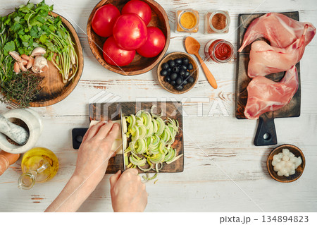 Preparing ingredients for a meal with fresh vegetables, meats, and spices in a kitchen setting Preparing ingredients for a meal with fresh vegetables, meats, and spices in a kitchen setting 134894823