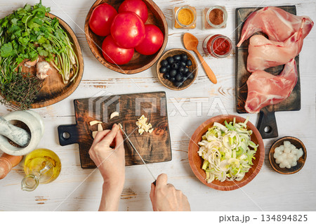Person is chopping garlic at a kitchen table Person is chopping garlic at a kitchen table 134894825