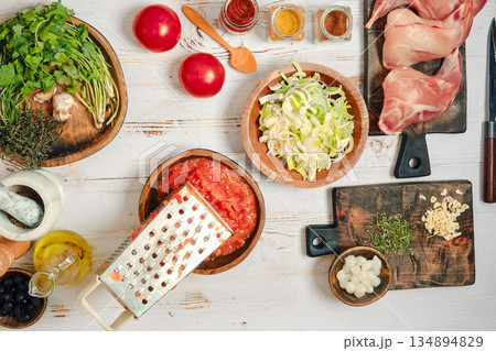 Cooking chicken with fresh ingredients on a wooden table in a kitchen setting during day time 134894829