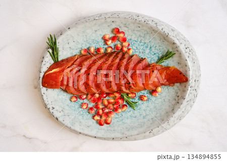 Sliced smoked turkey meat with pomegranate seeds on a plate with fresh herbs Sliced smoked turkey meat with pomegranate seeds on a plate with fresh herbs 134894855