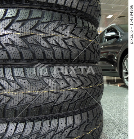 New car tires stacked up on the floor in front of car at service station  134894966