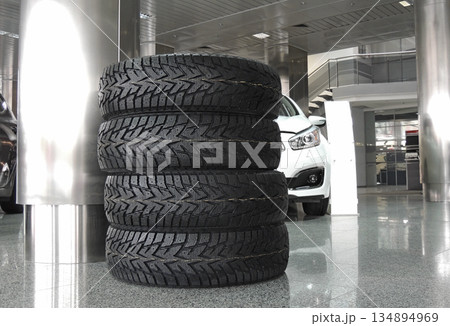 Stacked tires in front of the car in dealership showroom Stacked tires in front of the car in dealership showroom 134894969