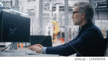 Senior Engineer Typing Dual Screen Workstation, Monitoring 3D Robotic Model on Screen Senior Engineer Typing Dual Screen Workstation, Monitoring 3D Robotic Model on Screen 134896856