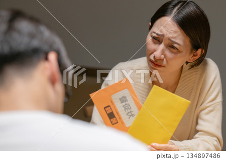 督促状を見て悩む男女 督促状を見て悩む男女 134897486