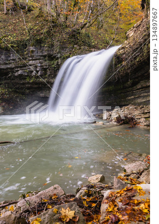 Vertical view a waterfall is flowing into a pool of water. 134897667