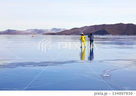 People are skating on the frozen Lake Baikal. Transparent ice. 134897830