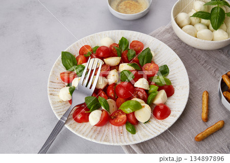 Caprese salad with cherry tomatoes , mozzarella cheese, basil 134897896