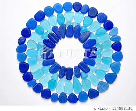 An artistic arrangement of blue sea glass pieces is shaped into a perfect circular mosaic pattern. An artistic arrangement of blue sea glass pieces is shaped into a perfect circular mosaic pattern. 134898136