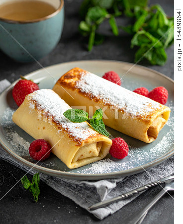 A plate of nalysnyky crepes is filled with sweet cheese and dusted with powdered sugar for dessert. A plate of nalysnyky crepes is filled with sweet cheese and dusted with powdered sugar for dessert. 134898641