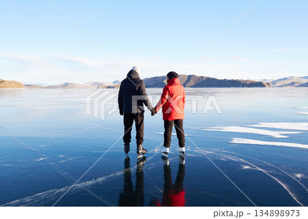 A couple is skating on the frozen Lake Baikal. Transparent ice. 134898973