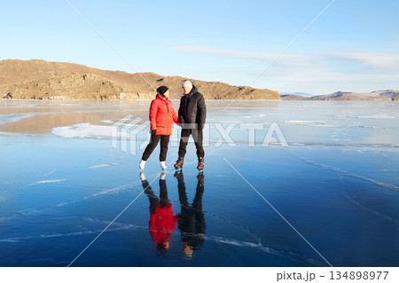 A couple skates on frozen Lake Baikal. The ice is clear. 134898977