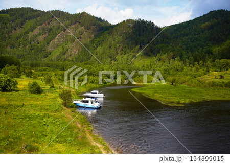 The yachts are located on the shore of a river or lake in a picturesque location. Around the forest, mountains. The yachts are located on the shore of a river or lake in a picturesque location. Around the forest, mountains. 134899015