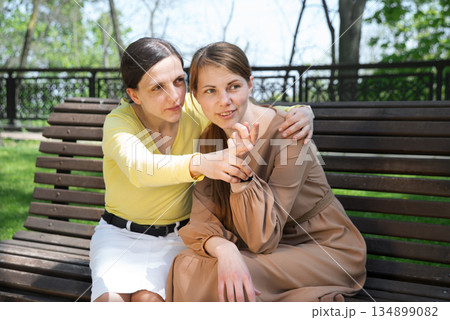Girls gossiping on a bench in the park 134899082
