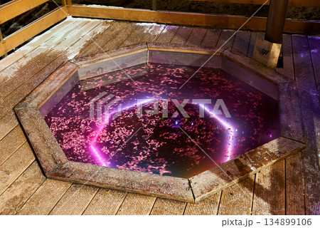 Calm and restful soak in cedar tub surrounded by snow and ambient lighting Calm and restful soak in cedar tub surrounded by snow and ambient lighting 134899106