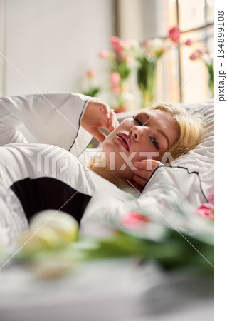 Cozy scene with flowers and sunlight, Casual woman listening to call surrounded by tulips and gentle light 134899108