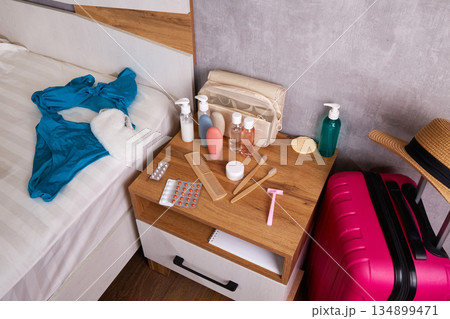 There are hygiene items and a travel set of cosmetics on the bedside table in a hotel room or bedroom. 134899471