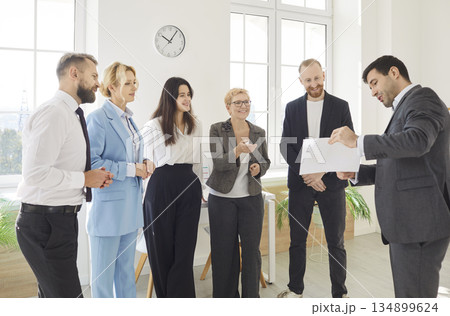 Diverse business happy team stands discussing project at corporate briefing in boardroom Diverse business happy team stands discussing project at corporate briefing in boardroom 134899624