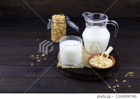 Oatmeal milk in a jug and a glass, oats in a jar, oatmeal flakes in a bowl Oatmeal milk in a jug and a glass, oats in a jar, oatmeal flakes in a bowl 134899740