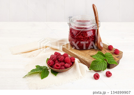 A jar of raspberry jam and a bowl of fresh berries. 134899907