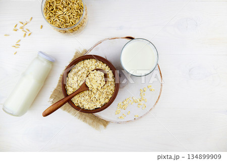 Oatmeal milk in a glass and a bottle, oatmeal flakes in a ceramic bowl 134899909