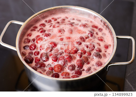 Bubbling red strawberry berries create a vibrant mixture as they simmer in a pot. Bubbling red strawberry berries create a vibrant mixture as they simmer in a pot. 134899923