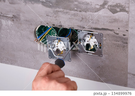 Home electrical repair in progress with tools and wiring on the wall 134899976