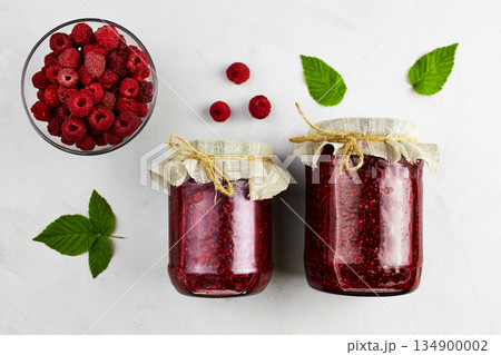 Jars of raspberry jam and fresh berries on light background. 134900002
