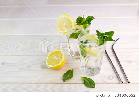 Two glasses with lemonade or mojito on wooden background. Fresh cold refreshing summer cocktail with lemon, mint and ice Two glasses with lemonade or mojito on wooden background. Fresh cold refreshing summer cocktail with lemon, mint and ice 134900052