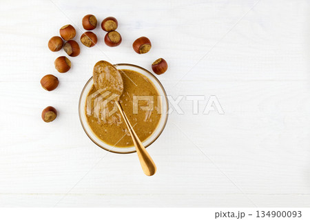 Natural organic raw hazelnut paste in a glass bowl and hazelnuts 134900093