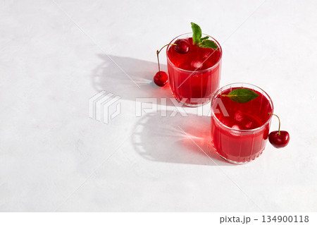 Cherry cocktail with ice on a light grey background. Top view, copy space. 134900118
