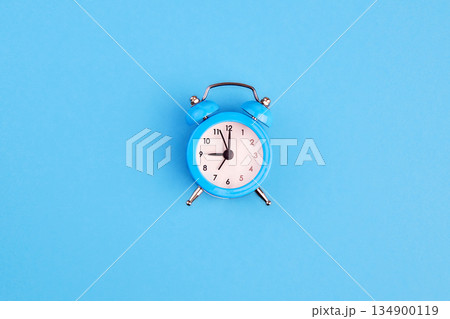 Classic alarm clock on blue background. Top view, copy space. 134900119